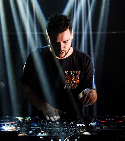 A man promoting music while djing in front of a light beam.