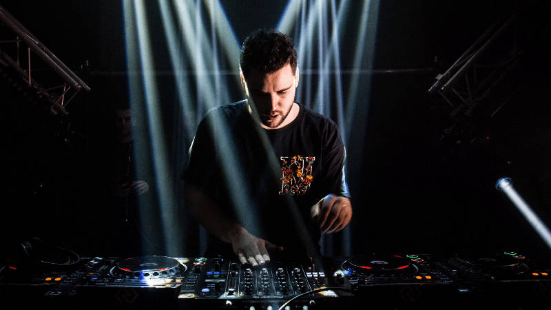 A man promoting music while djing in front of a light beam.