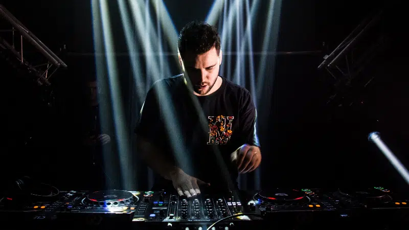 A man promoting music while djing in front of a light beam.