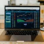 A laptop is sitting on a table next to a cup of coffee, highlighting the use of data analytics tools.