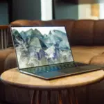 A laptop displaying NFT's sitting on a wooden table in a living room.