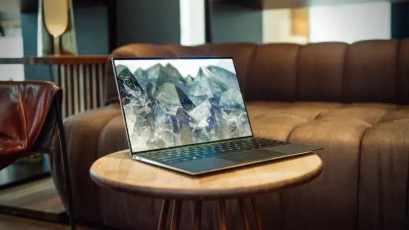 A laptop displaying NFT's sitting on a wooden table in a living room.