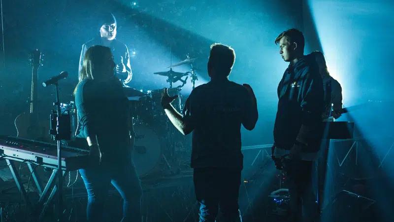 A group of people standing on stage in front of a bright light.