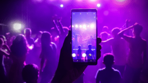 A person capturing a concert moment on their smartphone for social media sharing.