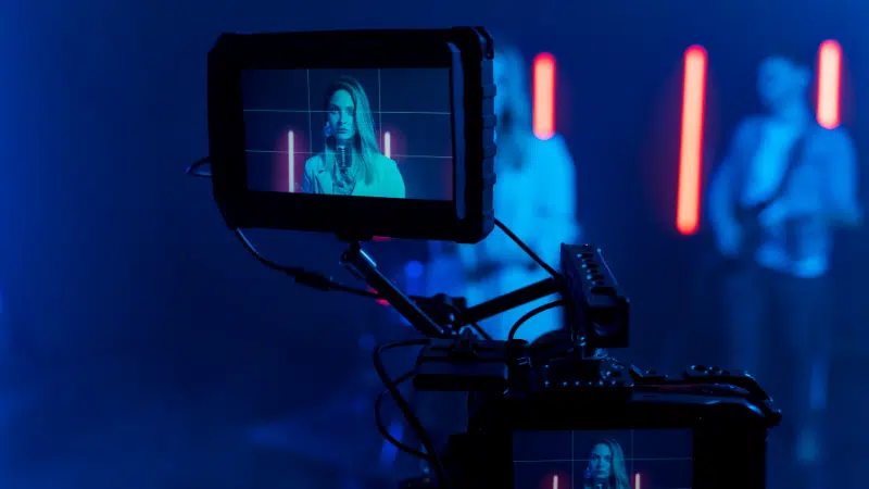 A YouTube camera on a tripod in front of a stage.