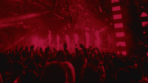 A crowd of people at a concert with red lights is an exhilarating experience for musicians performing on stage. It serves as a mesmerizing visual backdrop and further enhances the energy and atmosphere of the music.