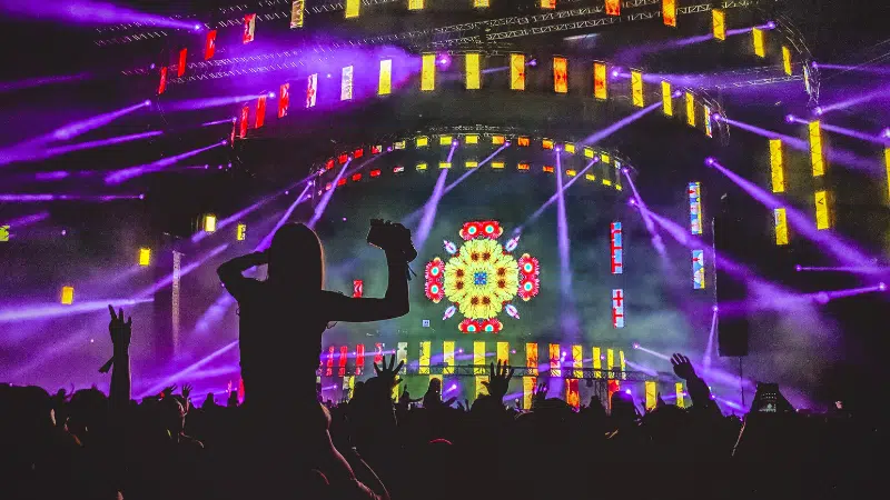 A crowd of people at a concert in the Metaverse with colorful lights.