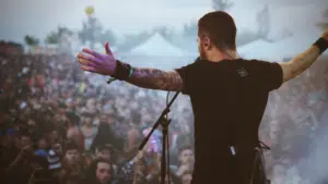 A man touring at a music festival with his arms out in front of a crowd.