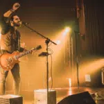 A man on stage with a microphone releasing his music.