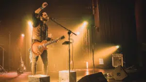 A man on stage with a microphone releasing his music.