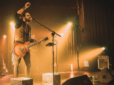 A man on stage with a microphone releasing his music.
