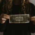 A woman showcasing advances in her kitchen with a one dollar bill.