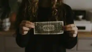 A woman showcasing advances in her kitchen with a one dollar bill.