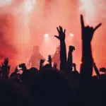 A tour concert with people raising their hands in the air.