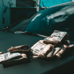 A pile of money representing passive income on the hood of a car.