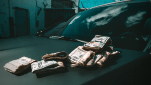 A pile of money representing passive income on the hood of a car.