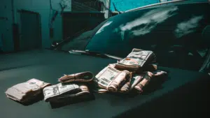 A pile of money representing passive income on the hood of a car.