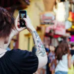 A woman is taking a picture with her cell phone for Instagram.