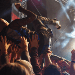 A man is being launched into the air at a concert, revealing the fanbase's enthusiasm.