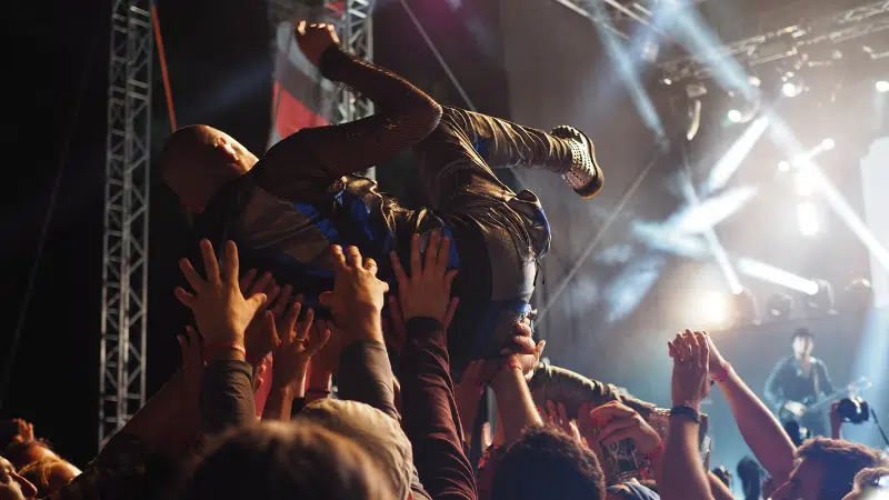 A man is being launched into the air at a concert, revealing the fanbase's enthusiasm.