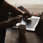 A man utilizing social media marketing on a laptop with a cup of coffee.