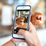 A person capturing an Instagram-worthy photo of a donut on their phone.