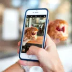 A person capturing an Instagram-worthy photo of a donut on their phone.