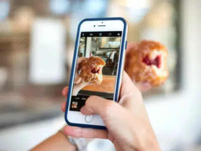 A person capturing an Instagram-worthy photo of a donut on their phone.