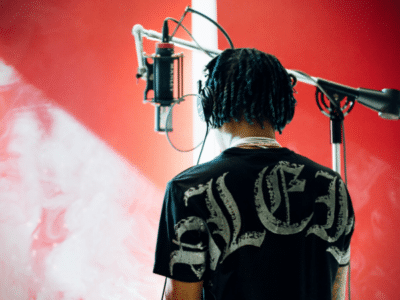 A man with dreadlocks performing on a microphone for SoundCloud.