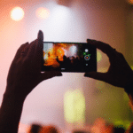 A person capturing UGC of a concert using a cell phone.