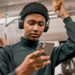 A man on a subway scrolling through Instagram on his phone.