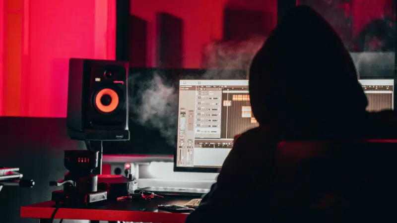 A person in a hoodie sitting in front of a computer exploring NFTs.