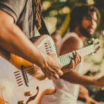 A group of people playing guitar at a music festival, promoting pre-saves.