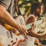 A group of people playing guitar at a music festival, promoting pre-saves.