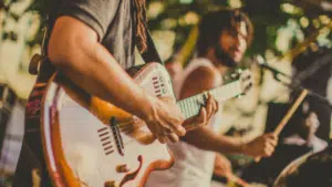 A group of people playing guitar at a music festival, promoting pre-saves.