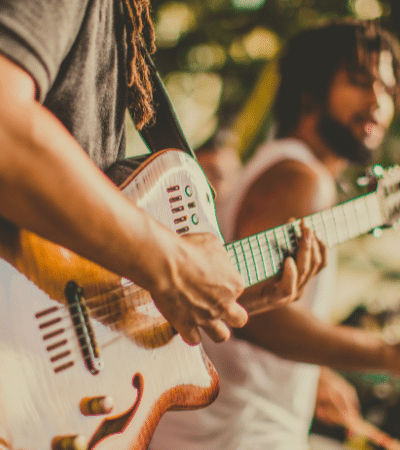 A group of people playing guitar at a music festival, promoting pre-saves.