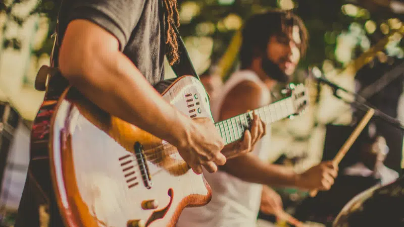 A group of people playing guitar at a music festival, promoting pre-saves.