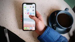 A person holding an iPhone on a table.