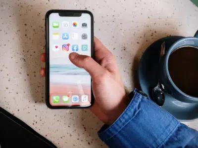 A person holding an iPhone on a table.
