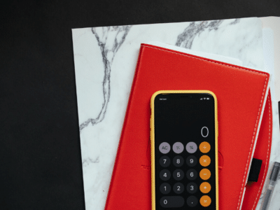 A red notebook for marketing budget planning with a calculator and pen.