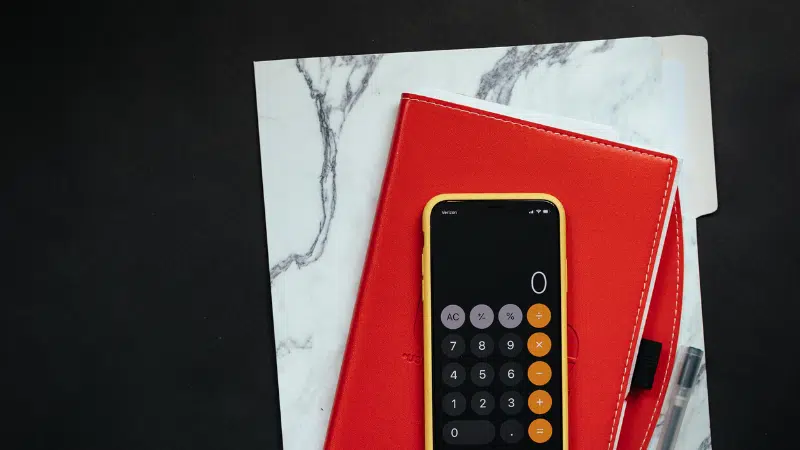 A red notebook for marketing budget planning with a calculator and pen.