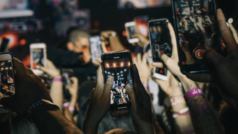 A group of people using Instagram at a concert.
