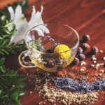 A cup of herbal tea with calming herbs and flowers on a peaceful wooden table.