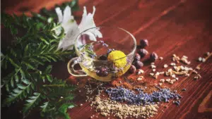 A cup of herbal tea with calming herbs and flowers on a peaceful wooden table.