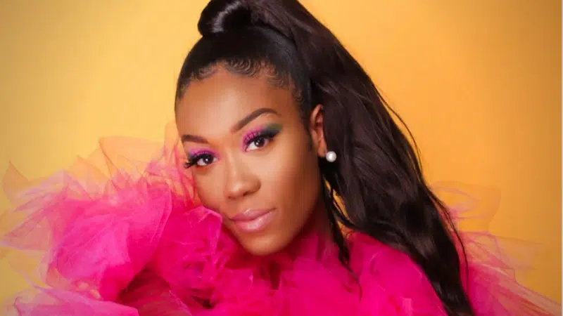 A woman in a pink dress posing for the invitation photo.