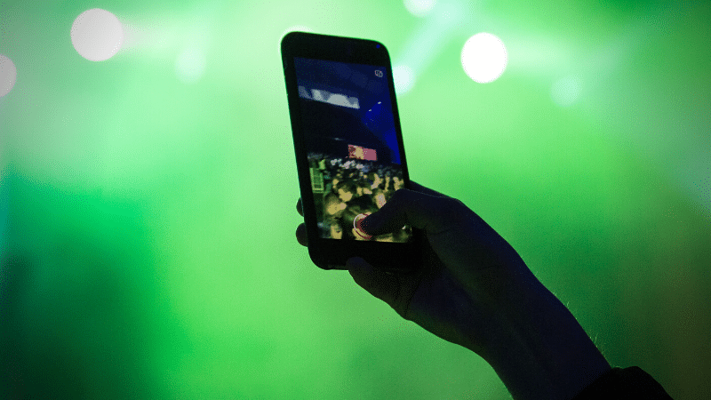 A person is capturing a concert moment with their cell phone for an Instagram Reels video.