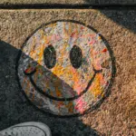 A pair of shoes promoting mental health with a smiley face painted on them.