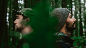 Two men in a forest looking at each other.