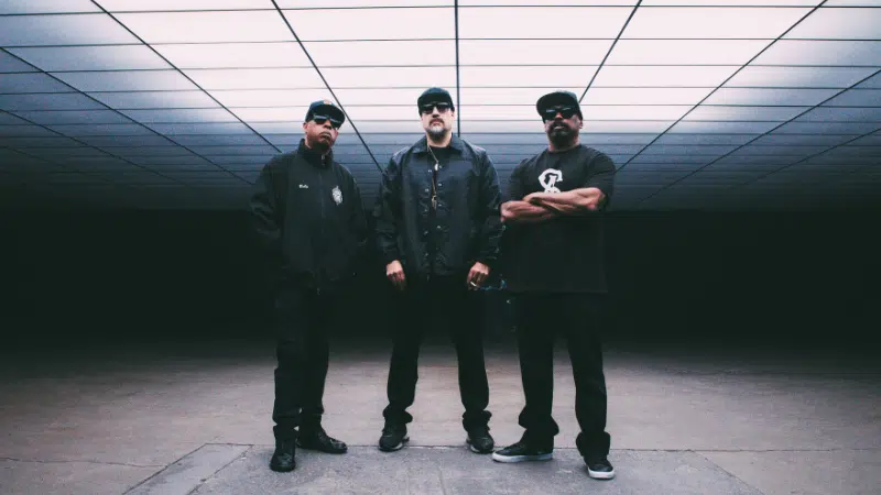 Three men standing in a dark room.