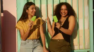 Two young women holding ice creams in front of a building.